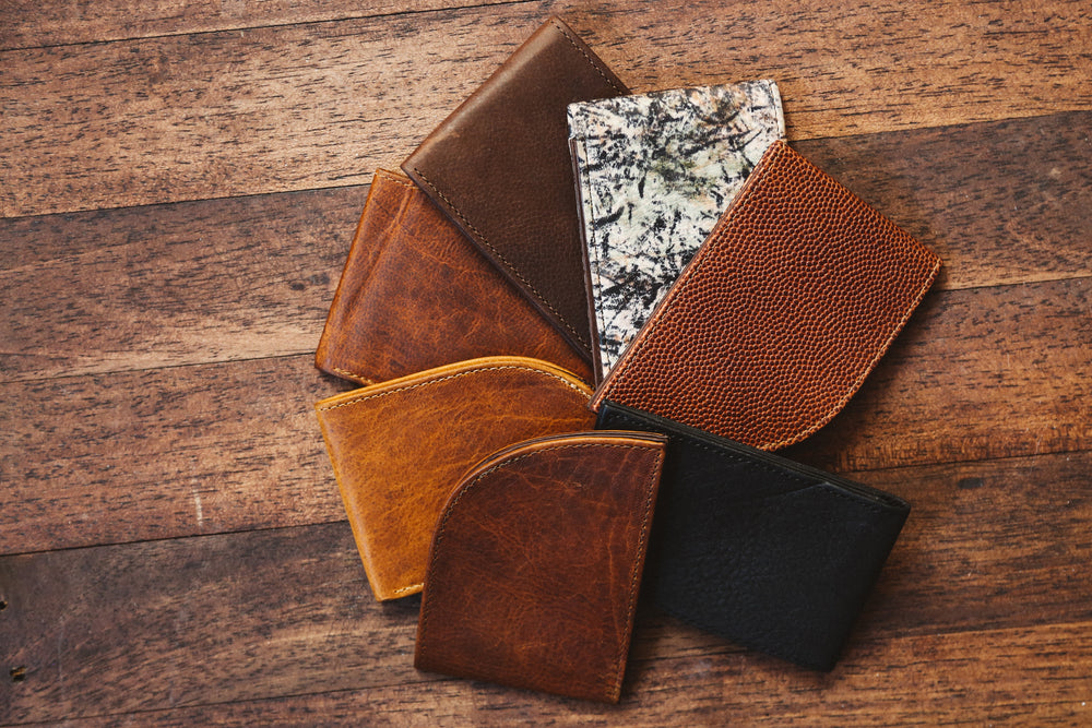 A group of leather wallets on a wooden floor.