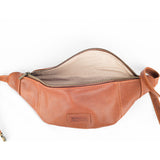 A Crescent Leather Sling Bag with the main zipper open, revealing a beige interior lining and a logo patch that reads "Rogue Industries" on the front.