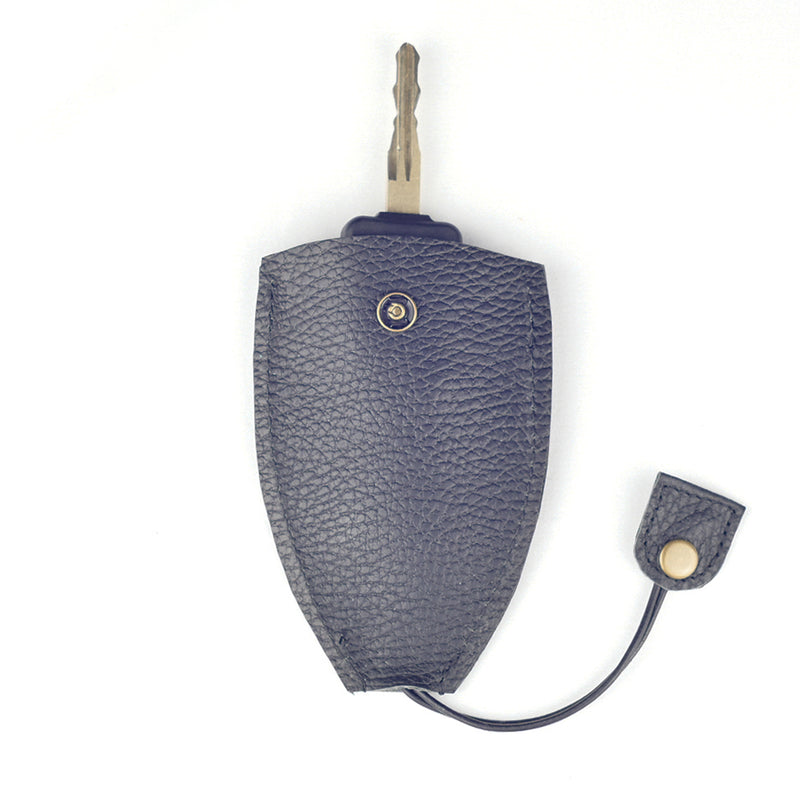 A key partially inserted in a Rogue Leather Key Protective Case by Rogue Industries, featuring a black textured durable cowhide with a snap button and dangling flap.