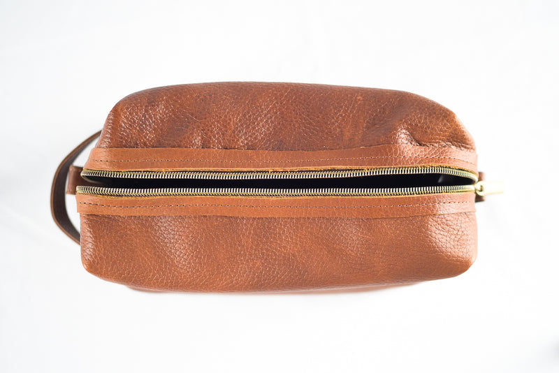 Top view of a Rogue Industries Leather Dopp Kit, crafted from genuine leather, featuring a visible zipper and handle, set against a white background.