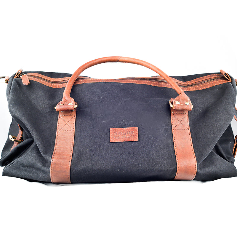 A White Cap Waxed Canvas Duffle by Rogue Industries with water-resistant properties, featuring brown leather straps and handles for durability.
