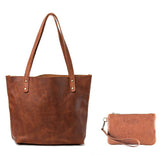 A brown leather tote bag crafted from top-grain leather with two handles is paired with a small matching Sebago Leather Clutch by Rogue Industries, made in the USA, featuring a convenient wrist strap.